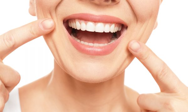 Young woman with beautiful smile on white background, closeup. Teeth whitening